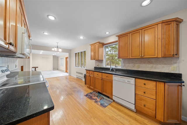 kitchen with light wood finished floors, an inviting chandelier, a sink, brown cabinetry, and white appliances