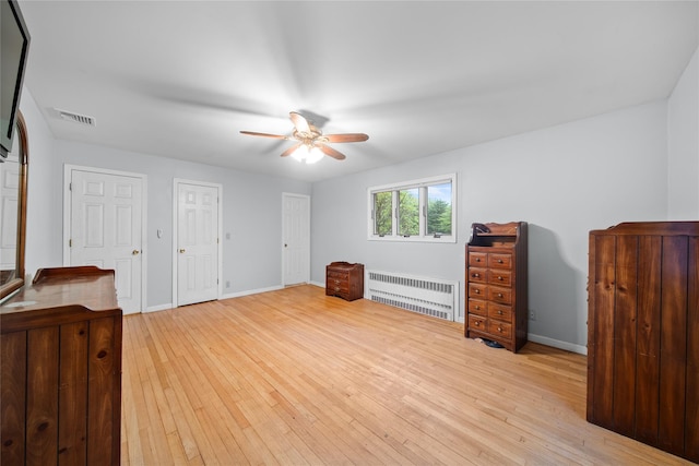 unfurnished bedroom with baseboards, light wood-style floors, radiator heating unit, and visible vents