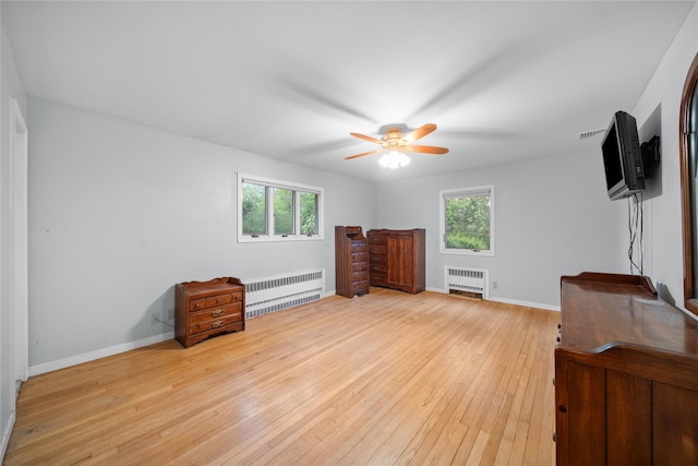 unfurnished bedroom with light wood-style flooring, multiple windows, and radiator heating unit