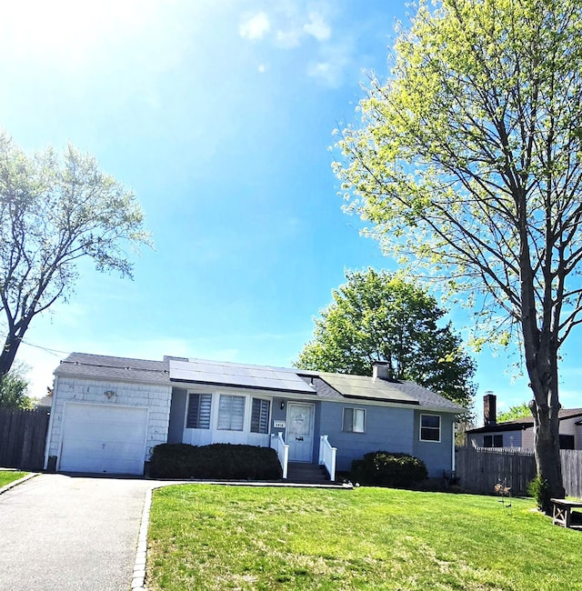 ranch-style house featuring aphalt driveway, fence, an attached garage, and a front lawn