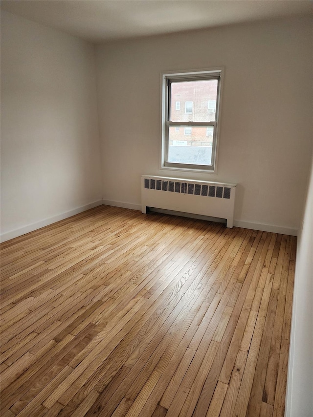 empty room with radiator, baseboards, and hardwood / wood-style floors