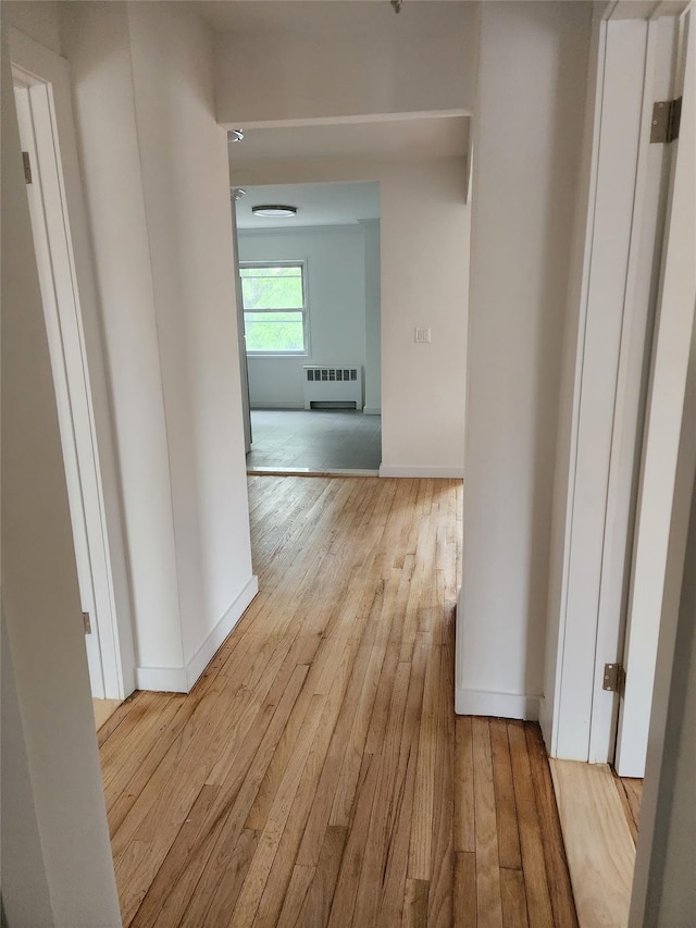 hallway featuring radiator, baseboards, and wood-type flooring