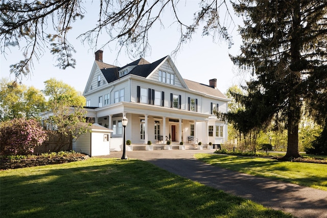 view of front of home with a porch, a chimney, and a front yard