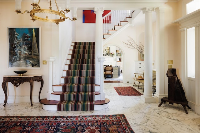 entrance foyer with marble finish floor, ornate columns, and stairs