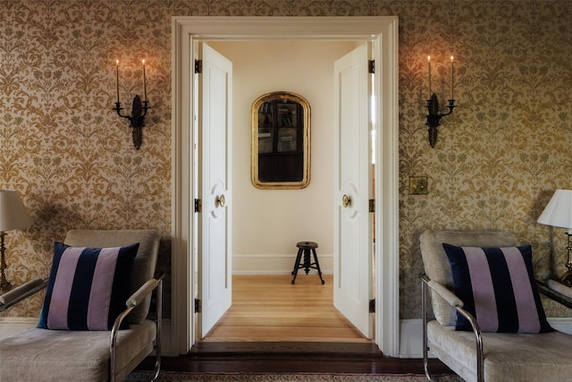 corridor with baseboards, wallpapered walls, and wood finished floors