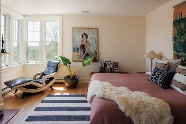 bedroom featuring wood finished floors, crown molding, visible vents, baseboards, and baseboard heating
