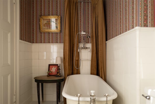bathroom with a freestanding bath, tile walls, wallpapered walls, and a wainscoted wall