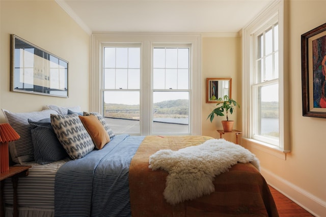 bedroom featuring wood finished floors, baseboards, and ornamental molding
