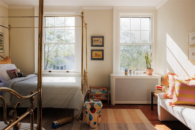 bedroom with radiator, ornamental molding, and wood finished floors