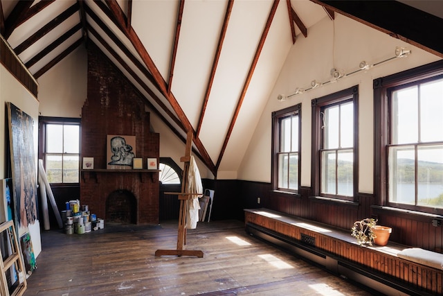 interior space with wainscoting, a baseboard radiator, beamed ceiling, and hardwood / wood-style flooring
