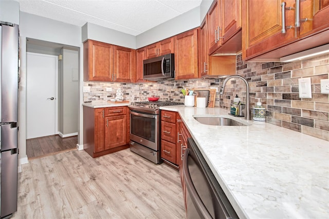 680 W Boston Post Rd Unit 3R, Mamaroneck, NY 10543 - kitchen featuring stainless steel appliances, a sink, brown cabinetry, light wood finished floors, and backsplash