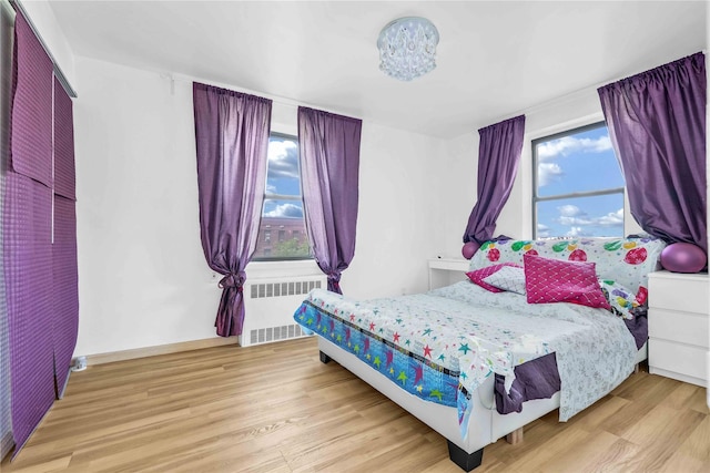 bedroom with radiator and light wood finished floors