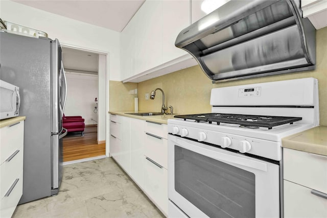 kitchen with white appliances, a sink, exhaust hood, light marble finish flooring, and white cabinetry