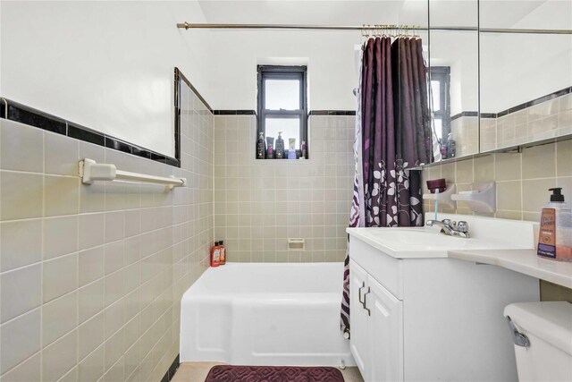 full bath featuring tile walls, toilet, shower / bath combo with shower curtain, and vanity