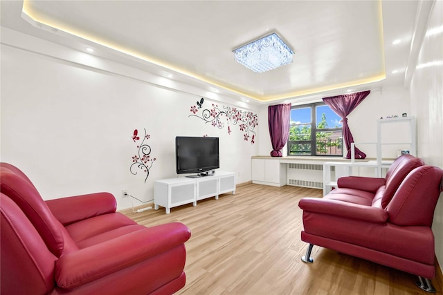 living room featuring a tray ceiling, radiator, wood finished floors, recessed lighting, and baseboards