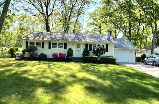 ranch-style house with an attached garage, driveway, a front yard, and a chimney