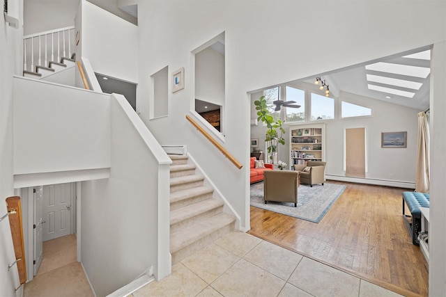 8 Wolf Rd, Croton-On-Hudson, NY 10520 - staircase with a baseboard heating unit, high vaulted ceiling, a skylight, ceiling fan, and tile patterned flooring