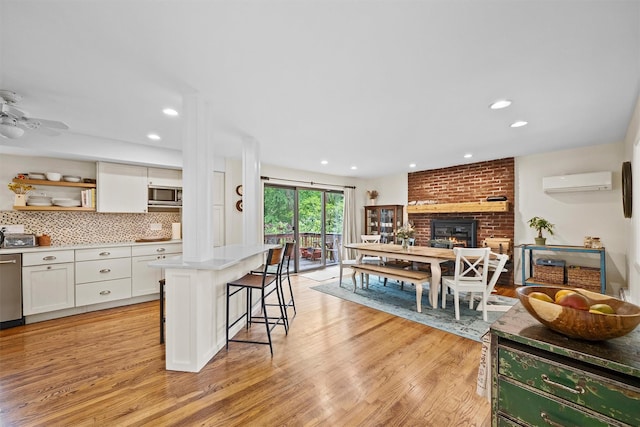 8 Wolf Rd, Croton-On-Hudson, NY 10520 - kitchen with appliances with stainless steel finishes, an AC wall unit, white cabinets, open shelves, and a kitchen breakfast bar