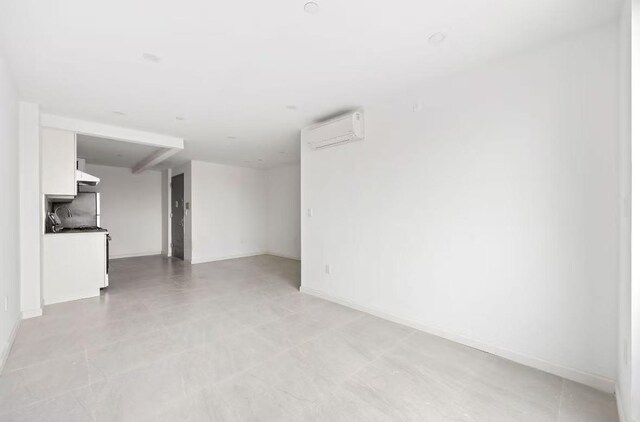 unfurnished living room featuring baseboards and a wall unit AC