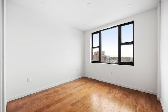 spare room featuring baseboards and light wood-type flooring