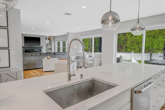 56 N Woods Rd, Baiting Hollow, NY 11933 - kitchen with a sink, white cabinets, light wood finished floors, light stone counters, and pendant lighting