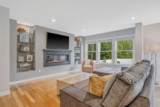 56 N Woods Rd, Baiting Hollow, NY 11933 - living area featuring a glass covered fireplace, wood finished floors, recessed lighting, built in shelves, and baseboards