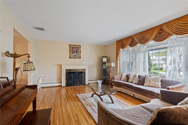 living room featuring a fireplace, wood finished floors, visible vents, and a baseboard heating unit