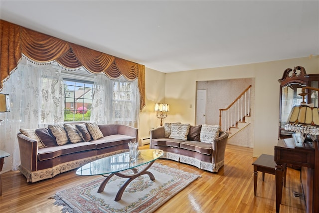 living area featuring a baseboard heating unit, stairway, and wood finished floors