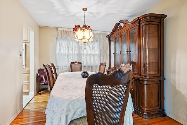 dining room with light wood finished floors, a chandelier, and baseboards