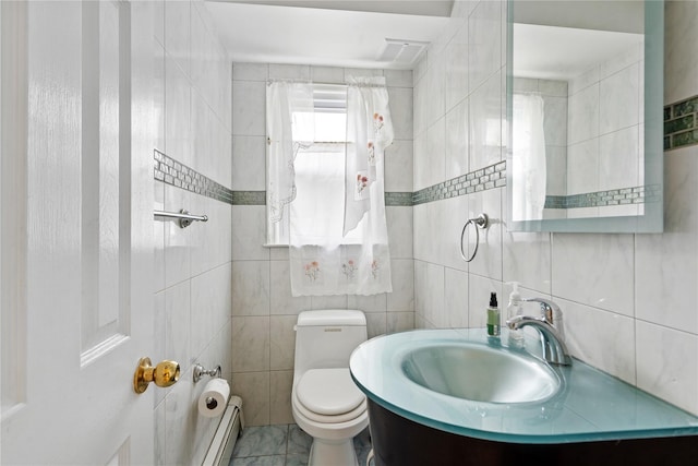bathroom with a baseboard heating unit, tile walls, toilet, and a sink