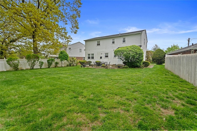 rear view of property featuring a yard and a fenced backyard