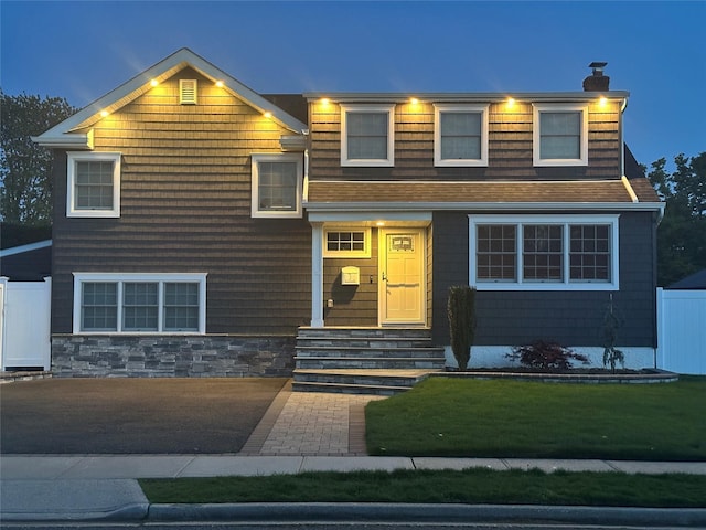 view of front of property featuring a front lawn, a shingled roof, fence, and a chimney