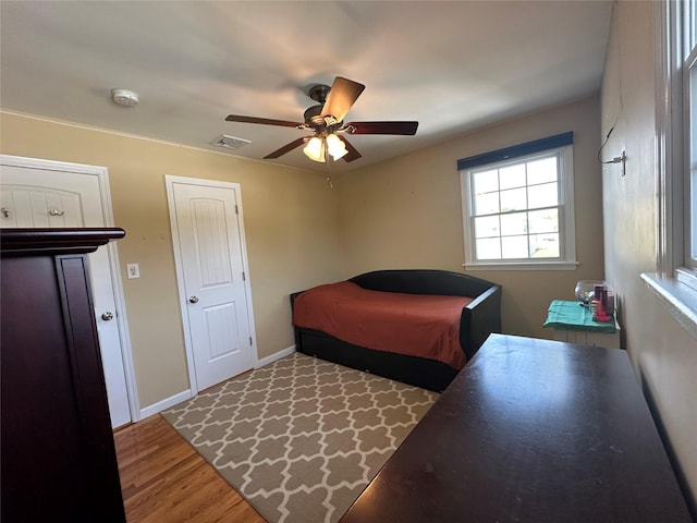 bedroom featuring a ceiling fan, baseboards, visible vents, and wood finished floors