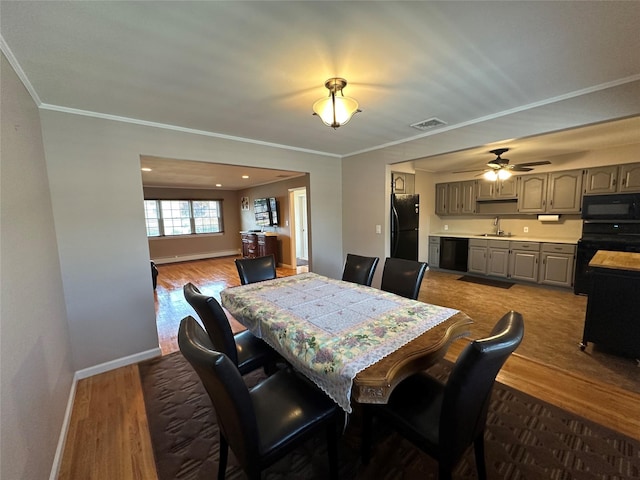 dining room with visible vents, baseboards, ornamental molding, and dark wood-style floors