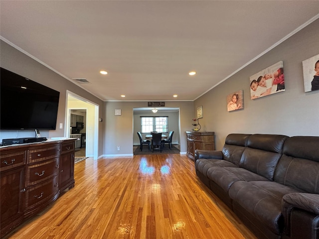 living room with light wood-type flooring, visible vents, ornamental molding, and recessed lighting
