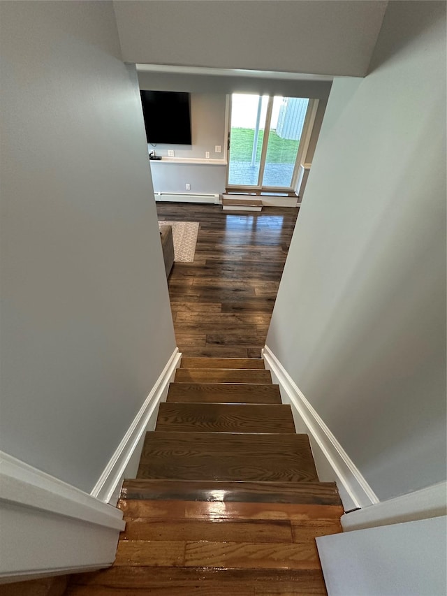 staircase featuring baseboards, baseboard heating, and wood finished floors