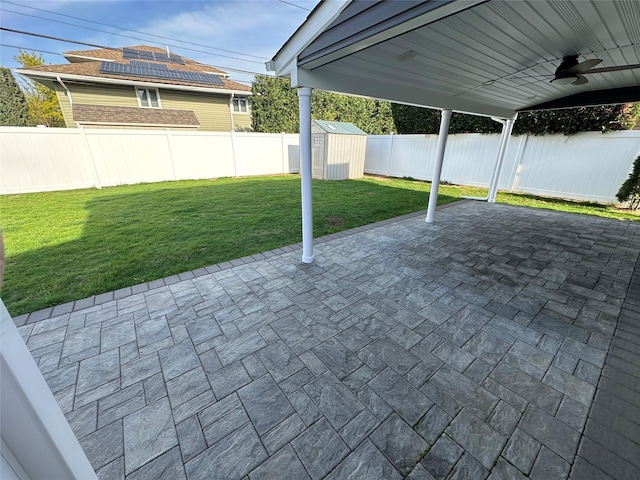 view of patio / terrace with an outbuilding, ceiling fan, a fenced backyard, and a storage unit