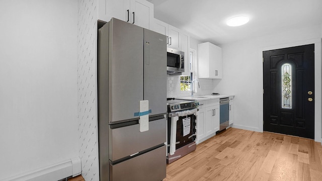 2227 Boller Ave, Bronx, NY 10475 - kitchen with appliances with stainless steel finishes, a sink, white cabinetry, and a baseboard heating unit