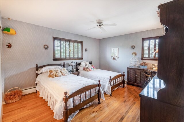 402 Spangle Dr, North Babylon, NY 11703 - bedroom featuring wallpapered walls, light wood finished floors, multiple windows, baseboard heating, and ceiling fan