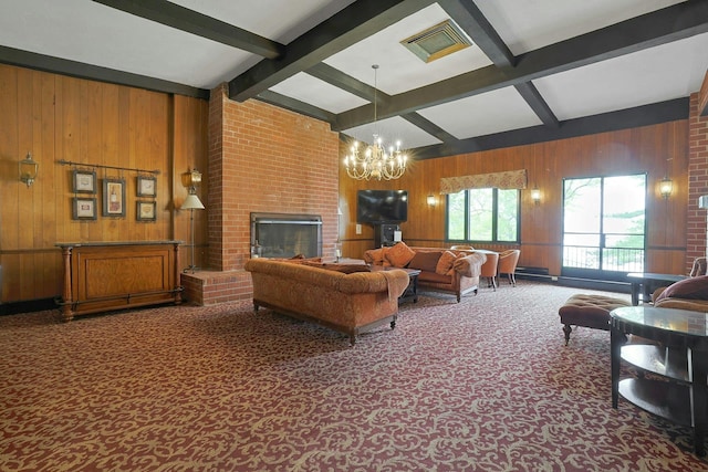 carpeted living area with wood walls, beam ceiling, a chandelier, and a brick fireplace