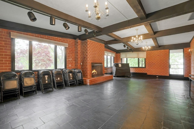 misc room with a chandelier, a brick fireplace, beamed ceiling, and brick wall