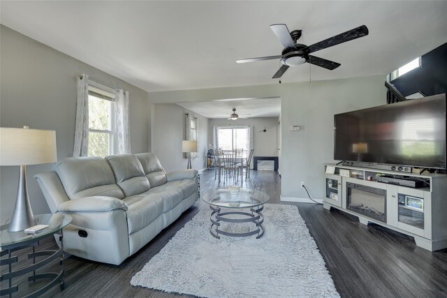 living area with a ceiling fan, dark wood finished floors, and baseboards