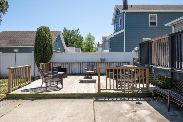 back of property with a fire pit, a deck, and fence