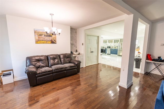 living room with baseboards, a chandelier, and dark wood-type flooring