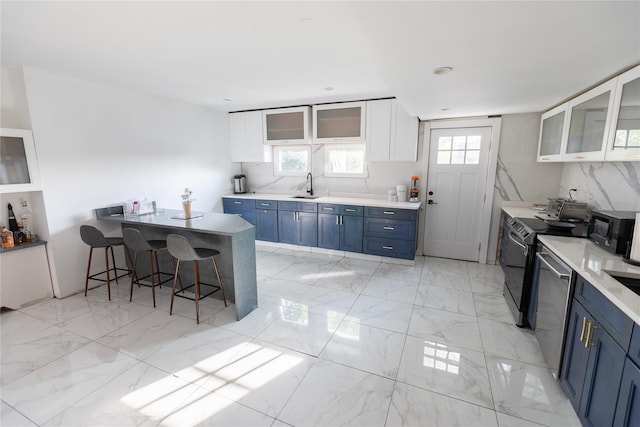 kitchen featuring a breakfast bar, a sink, black microwave, blue cabinetry, and white cabinets