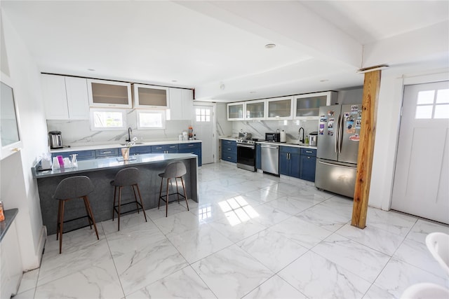 kitchen with appliances with stainless steel finishes, blue cabinets, a breakfast bar area, and a sink