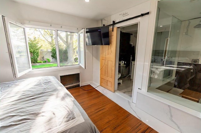 bedroom featuring recessed lighting, a barn door, and wood finished floors