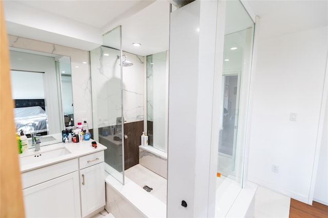 ensuite bathroom featuring connected bathroom, a marble finish shower, and vanity