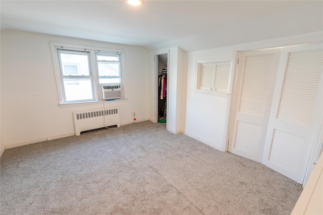 unfurnished bedroom featuring vaulted ceiling, carpet floors, and radiator heating unit