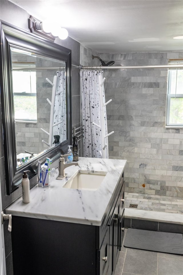 bathroom with tile patterned floors, vanity, and tiled shower
